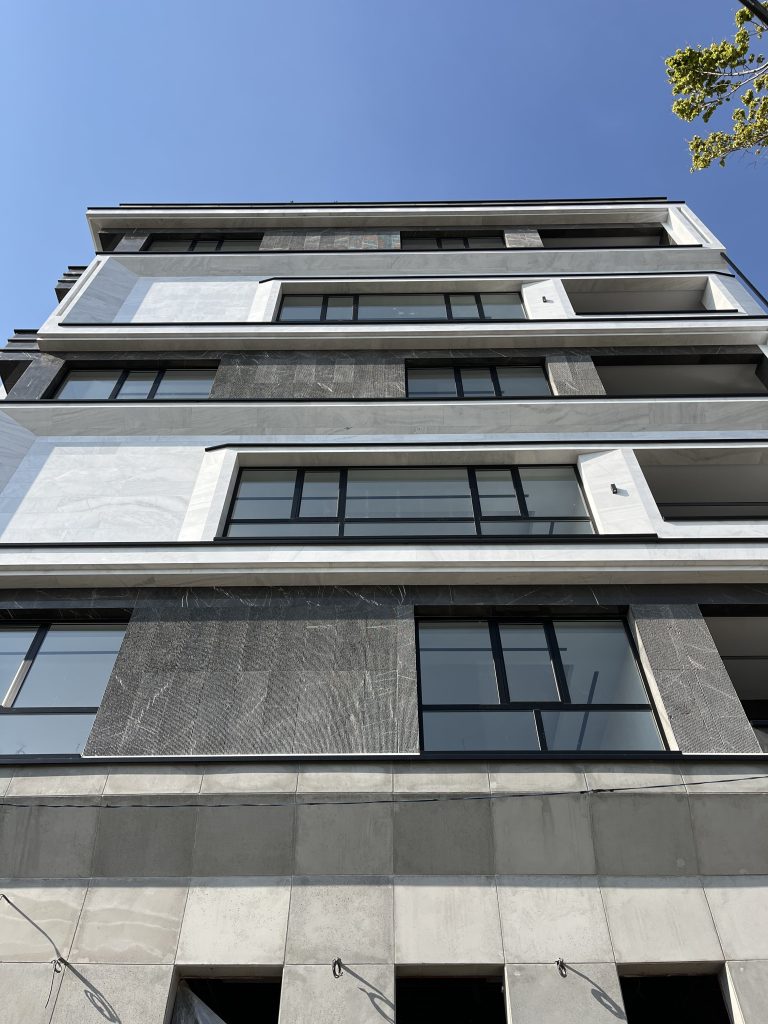 نمای اصلی ساختمان بامعماری مینیمال و استفاده از سنگ مرمر مشکی و سفید