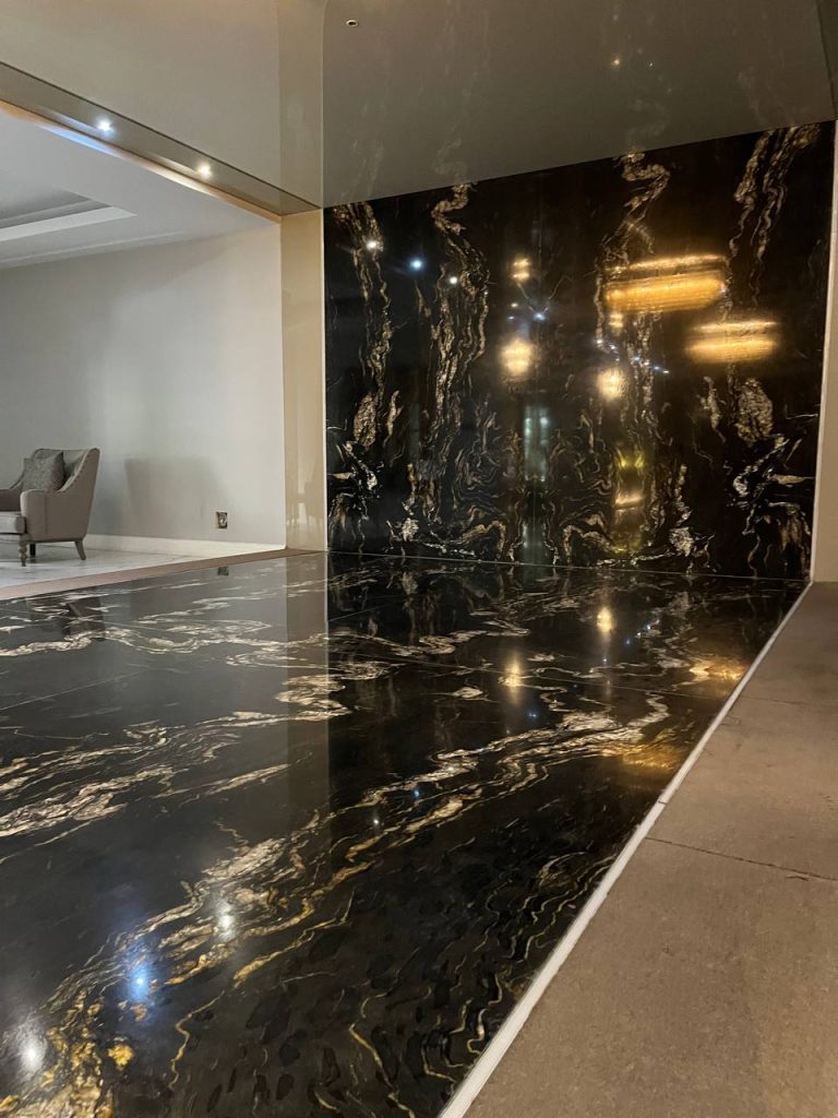 نمای زیبا از لابی لوکس یک ساختمان در تهران استفاده از سنگ گرانیت تیتانیوم هند با زمینه مشکی و رگه‌های طلایی در لابی - گروه سنگ المان