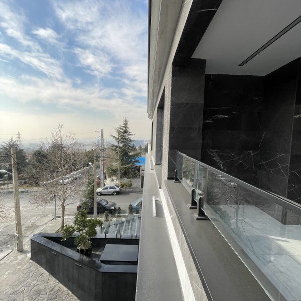 نمایی از تراس یک ساختمان که محوطه سازی جلوی ساختمان به وضوح دیده می شود.